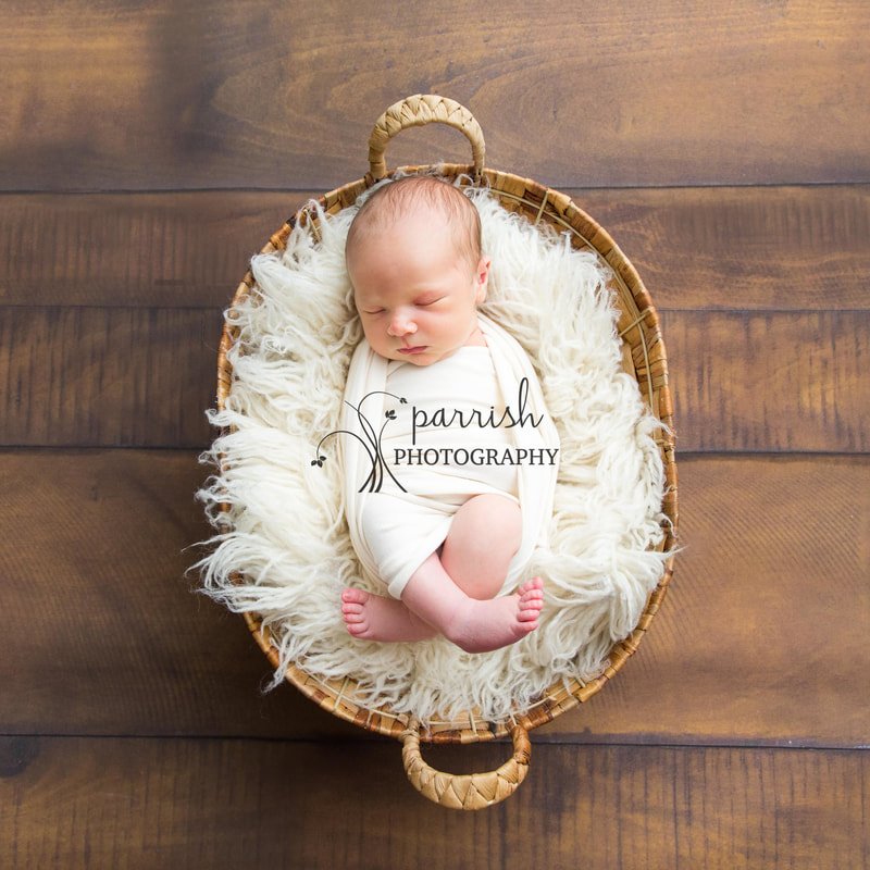 Newborn in a basket on oak floor